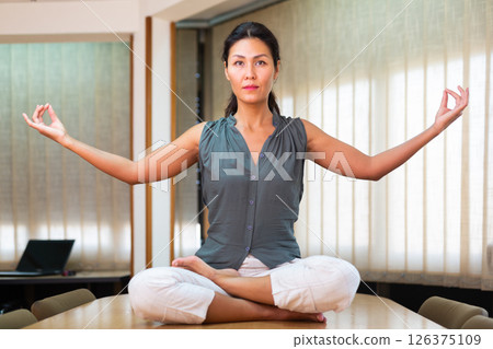 Businesswoman sitting at the table in lotus position 126375109