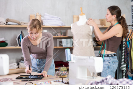 Female fashion designers create design clothes in the workshop Female fashion designers create design clothes in the workshop 126375125