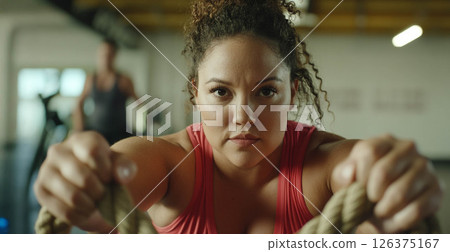 Plus size woman focused on training with battle ropes in the gym, showcasing strength and determination. Generated image 126375167
