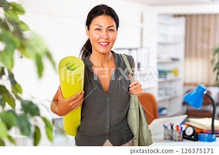Asian businesswoman holding yoga mat in office Asian businesswoman holding yoga mat in office 126375171