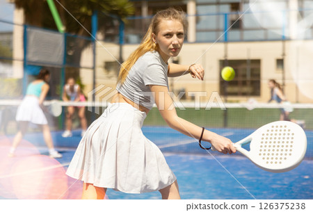 Young woman playing paddle tennis against team of women Young woman playing paddle tennis against team of women 126375238