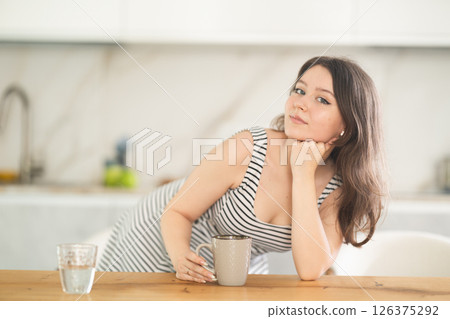Young woman with cup leaning on table 126375292