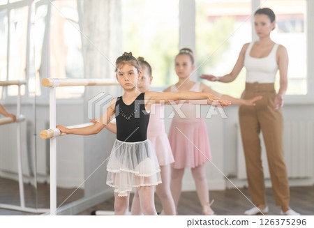 Girls in ballet class perform second position with correction of female mentor Girls in ballet class perform second position with correction of female mentor 126375296