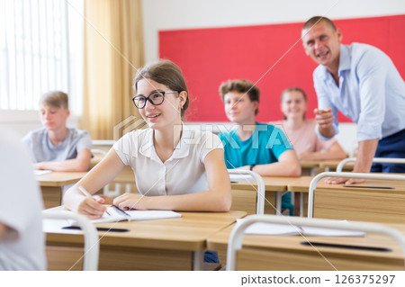 Cheerful teen girl in glasses studying in classroom Cheerful teen girl in glasses studying in classroom 126375297