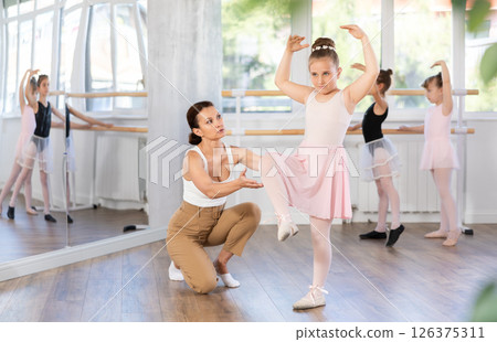 Woman teacher corrects movement of girl dancer Woman teacher corrects movement of girl dancer 126375311