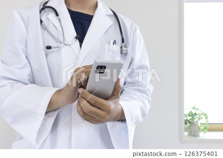 使用智慧型手機的醫生影像（日本人、男性、無臉、30 多歲） 126375401