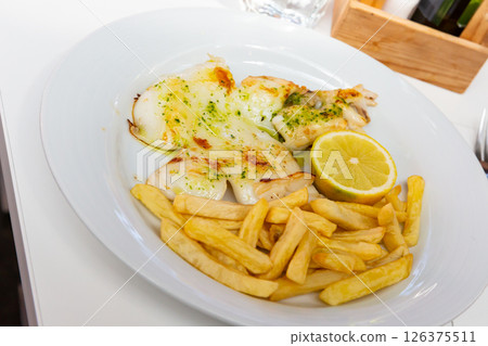 Roasted sepia with fried potatoes, green sauce and lemon 126375511