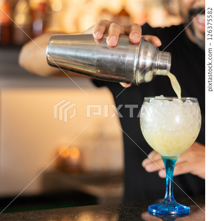 Bartender hand at counter and bar tabletop , he working, preparing to treat visitors with cocktail 126375582