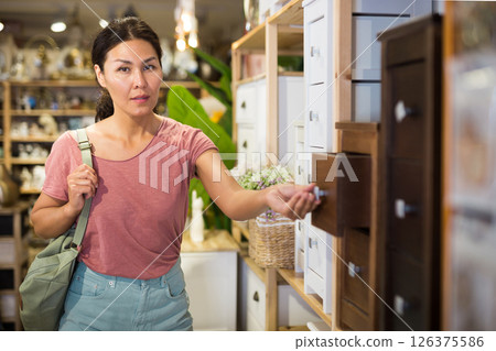 Asian female choosing wooden commode in store 126375586