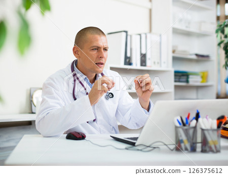 Doctor conducting online patient consultation in medical office 126375612