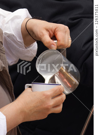 Barista Pouring Steamed Milk Into a Coffee Cup in a Cafe Setting 126375811