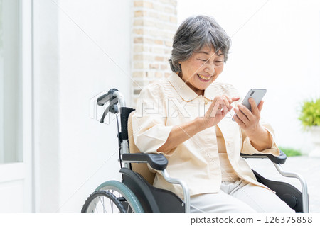 坐在輪椅上操作智慧型手機的高級女性 126375858