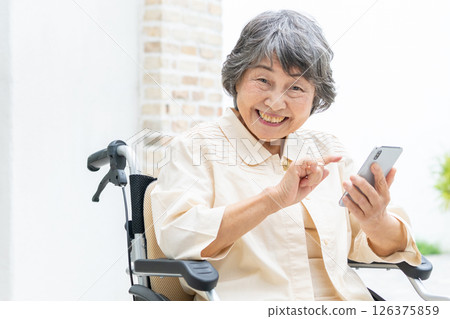 坐在輪椅上操作智慧型手機的高級女性 126375859