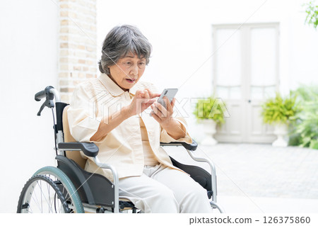 Senior woman in a wheelchair operating a smartphone Senior woman in a wheelchair operating a smartphone 126375860