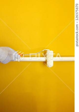A painter paints a pipe white with a roller, a gloved hand paints a pipe white with a roller 126375870