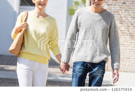 A lively senior couple going out holding hands A lively senior couple going out holding hands 126375919