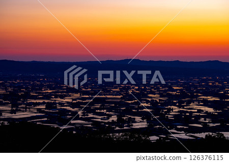 [Amazing early summer scenery] Sunset in the Tonami Plain, scattered villages, rice field reflections, and magic hour in early summer [Toyama Prefecture] 126376115