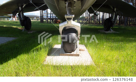 A close view of a vintage Soviet aircraft's landing gear positioned on a concrete slab amidst lush green grass and tall trees, reflecting aviation history. A close view of a vintage Soviet aircraft's landing gear positioned on a concrete slab amidst lush green grass and tall trees, reflecting aviation history. 126376148