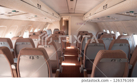The cabin of a vintage Soviet aircraft boasts neatly arranged seats and soft lighting, showcasing classic USSR aviation design. The cabin of a vintage Soviet aircraft boasts neatly arranged seats and soft lighting, showcasing classic USSR aviation design. 126376169