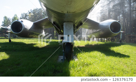 A vintage Soviet aircraft stands displayed in a lush green forest, highlighting its detailed craftsmanship and historical significance from the USSR period. A vintage Soviet aircraft stands displayed in a lush green forest, highlighting its detailed craftsmanship and historical significance from the USSR period. 126376170