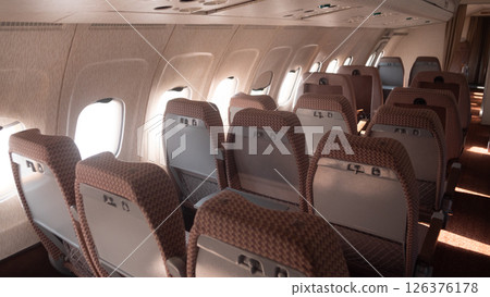 Empty passenger seats line the aisle of a Soviet-era airplane, featuring a vintage design that reflects the travel aesthetics of the USSR period. Empty passenger seats line the aisle of a Soviet-era airplane, featuring a vintage design that reflects the travel aesthetics of the USSR period. 126376178