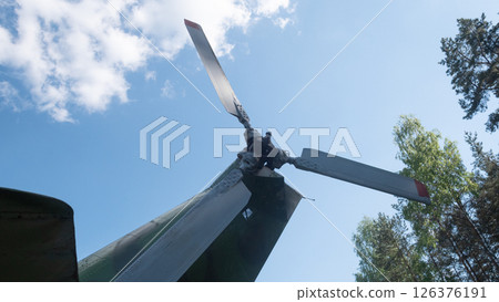 A close-up view of a vintage Soviet helicopter rotor, set against a bright blue sky, highlighting the detailed mechanics and historical significance in Russian aviation. A close-up view of a vintage Soviet helicopter rotor, set against a bright blue sky, highlighting the detailed mechanics and historical significance in Russian aviation. 126376191