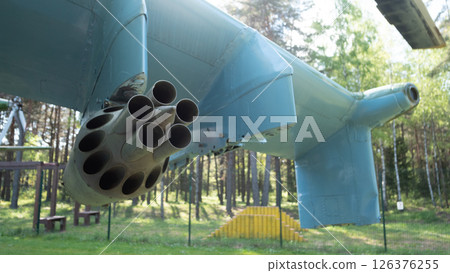 A close-up of a vintage Soviet aircraft showcasing a missile launcher. This military artifact is surrounded by lush greenery, highlighting its historical significance. A close-up of a vintage Soviet aircraft showcasing a missile launcher. This military artifact is surrounded by lush greenery, highlighting its historical significance. 126376255