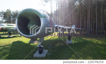 A vintage Soviet aircraft stands prominently in a museum nestled among tall trees, representing a significant piece of military and aviation heritage from the USSR. A vintage Soviet aircraft stands prominently in a museum nestled among tall trees, representing a significant piece of military and aviation heritage from the USSR. 126376258