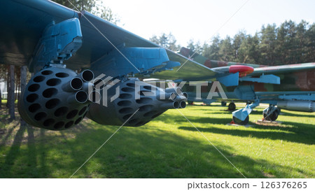 A vintage Soviet aircraft rests in a green park with missile pods prominently featured under the wings, reflecting the military advancements of the USSR. 126376265