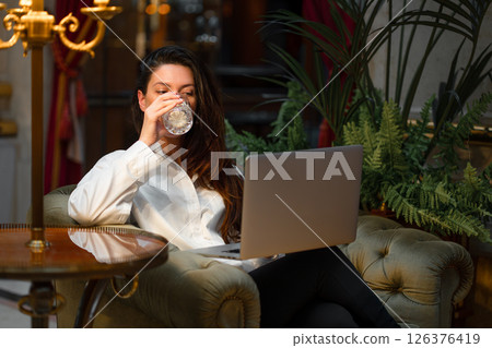 Businesswoman with laptop drinking alcohol sitting 126376419