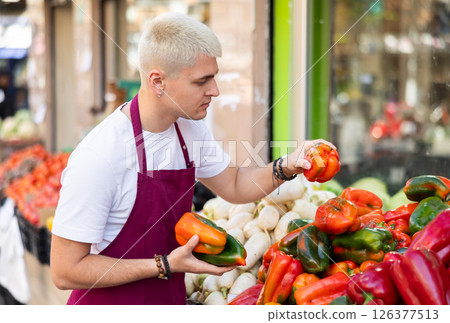 Guy shop seller puts bell pepper goods on display case Guy shop seller puts bell pepper goods on display case 126377513