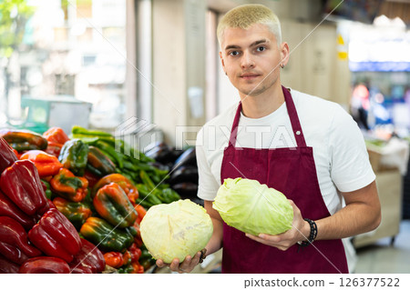 Grocery store employee places ripe cabbage on a display case at supermarket Grocery store employee places ripe cabbage on a display case at supermarket 126377522