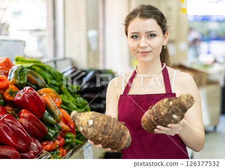 Portrait of positive girl seller with yucca root in her hands - work in grocery supermarket 126377532
