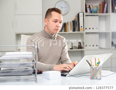 Man bookkeeper sitting at table and using laptop 126377577