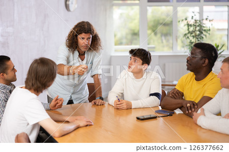 Man conducting meeting with male colleagues around table Man conducting meeting with male colleagues around table 126377662
