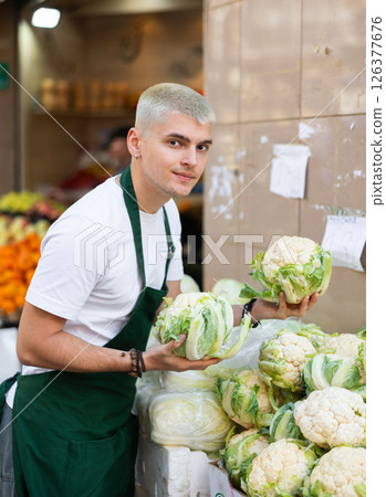 Grocery store employee places ripe broccoli on a display case at street store Grocery store employee places ripe broccoli on a display case at street store 126377676
