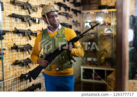 African american man in army uniform with weapon in military shop African american man in army uniform with weapon in military shop 126377717