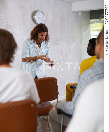 Man lecturing to group of men gathered in study hall 126377795