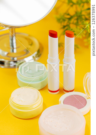 黃色背景上排列著彩色化妝品、花朵和鏡子的化妝圖像 黃色背景上排列著彩色化妝品、花朵和鏡子的化妝圖像 126378991