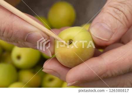 The process of making crispy plums using small plums. Remove the ends of the small plums with a bamboo skewer. 126380817