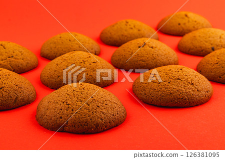 Warm ginger cookies arranged on a bright red surface 126381095