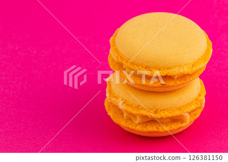 Bright yellow macarons arranged on vibrant pink background 126381150