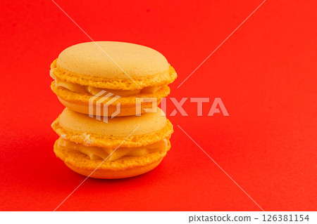 Delicious yellow macarons stacked on a vibrant red background Delicious yellow macarons stacked on a vibrant red background 126381154
