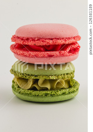 Colorful macaron desserts stacked on a white surface Colorful macaron desserts stacked on a white surface 126381189