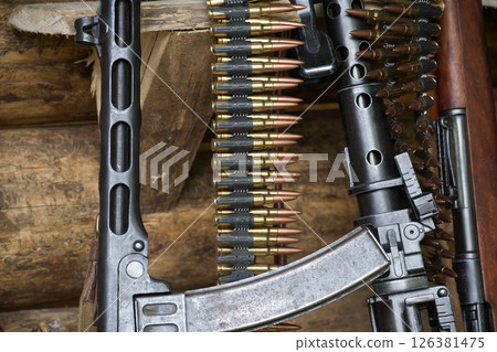 Close-Up of Machine Gun with Ammunition and Rifles Displayed in Rustic Setting Close-Up of Machine Gun with Ammunition and Rifles Displayed in Rustic Setting 126381475