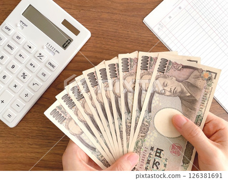 Woman's hands holding banknotes on a desk Woman's hands holding banknotes on a desk 126381691