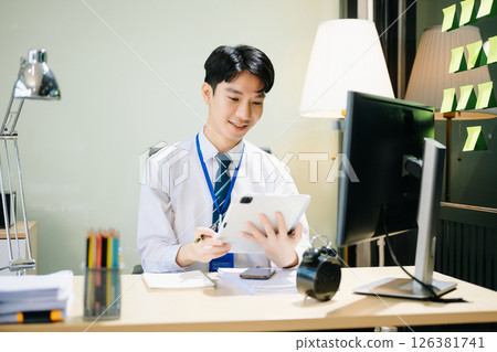 Young businessman working at office with laptop, tablet and taking notes on the paper. Young businessman working at office with laptop, tablet and taking notes on the paper. 126381741