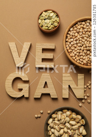Nuts and seeds in bowls and wooden letters on beige background, top view Nuts and seeds in bowls and wooden letters on beige background, top view 126381785