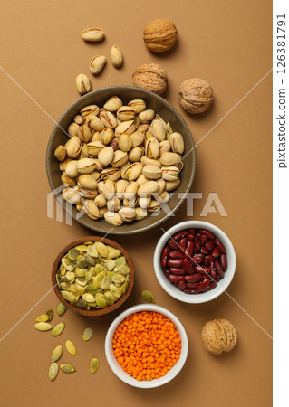 Beans, nuts and seeds in bowls on beige background, top view Beans, nuts and seeds in bowls on beige background, top view 126381791