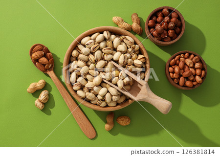 Different types of nuts in wooden bowls on a green background Different types of nuts in wooden bowls on a green background 126381814